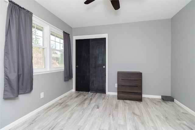 unfurnished bedroom featuring a closet, baseboards, ceiling fan, and wood finished floors
