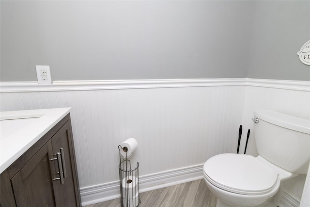 bathroom featuring vanity, wainscoting, toilet, and wood finished floors