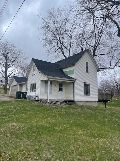 exterior space with a yard, cooling unit, and roof with shingles