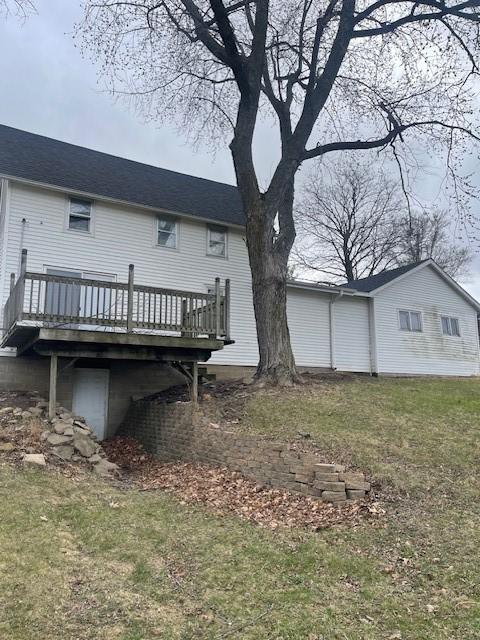 back of property with a deck and a lawn