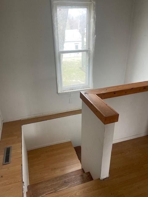 stairway featuring visible vents, baseboards, wood finished floors, and a healthy amount of sunlight