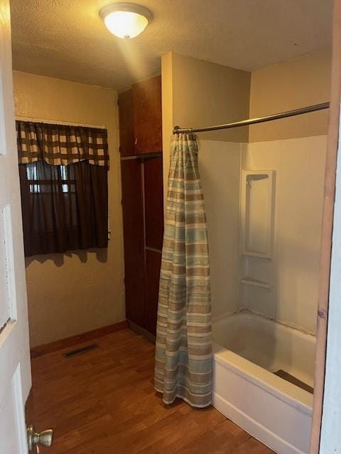 full bath featuring baseboards, shower / bath combination with curtain, a textured ceiling, visible vents, and wood finished floors