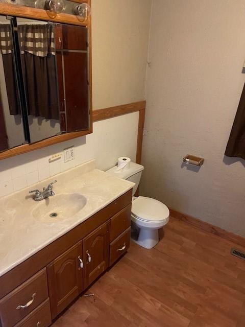 bathroom featuring vanity, visible vents, toilet, and wood finished floors