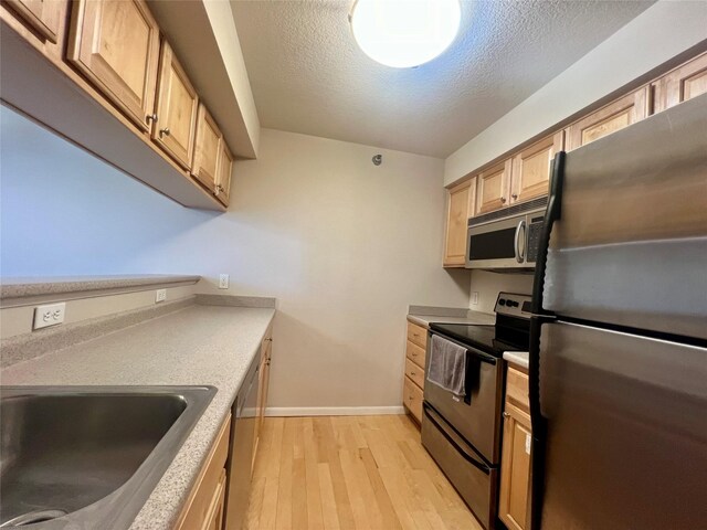 6440 Ep True Pkwy Unit 2307, West Des Moines, IA 50266 - kitchen featuring stainless steel appliances, light wood-style floors, a textured ceiling, light countertops, and light brown cabinets