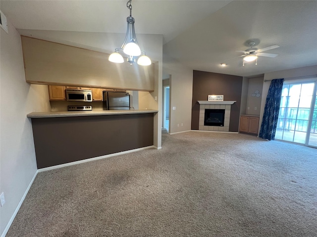 6440 Ep True Pkwy Unit 2307, West Des Moines, IA 50266 - kitchen featuring appliances with stainless steel finishes, carpet floors, ceiling fan, a tiled fireplace, and lofted ceiling