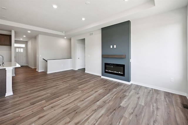 1609 Garland Ave, Norwalk, IA 50021 - unfurnished living room featuring wood finished floors, recessed lighting, a large fireplace, and a raised ceiling