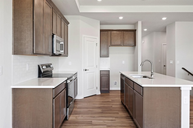 1609 Garland Ave, Norwalk, IA 50021 - kitchen with appliances with stainless steel finishes, light wood-style flooring, a center island with sink, decorative backsplash, and recessed lighting