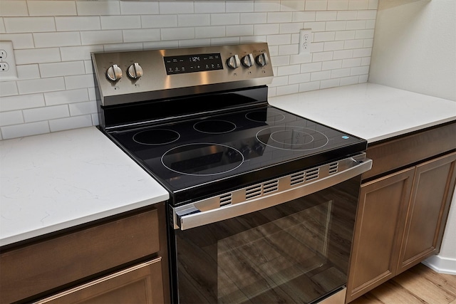1139 NW Petersen Dr, Waukee, IA 50263 - kitchen with stainless steel range with electric cooktop, decorative backsplash, and light stone countertops