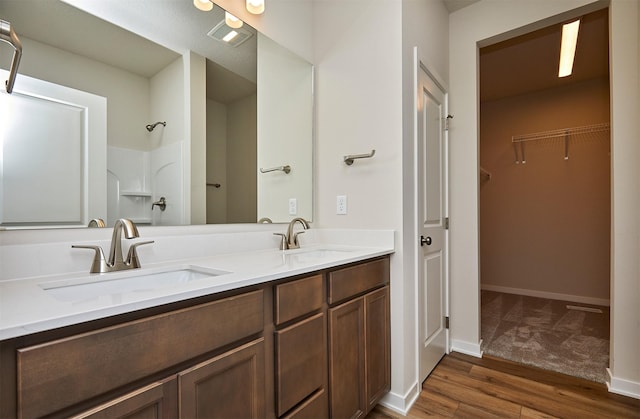 1139 NW Petersen Dr, Waukee, IA 50263 - bathroom with double vanity, wood finished floors, a walk in closet, and a shower