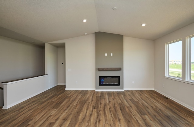 1139 NW Petersen Dr, Waukee, IA 50263 - unfurnished living room featuring dark wood finished floors, vaulted ceiling, a glass covered fireplace, and recessed lighting