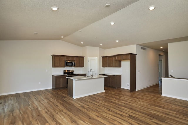 1139 NW Petersen Dr, Waukee, IA 50263 - kitchen featuring stainless steel microwave, black electric range oven, dark wood-type flooring, an island with sink, and lofted ceiling