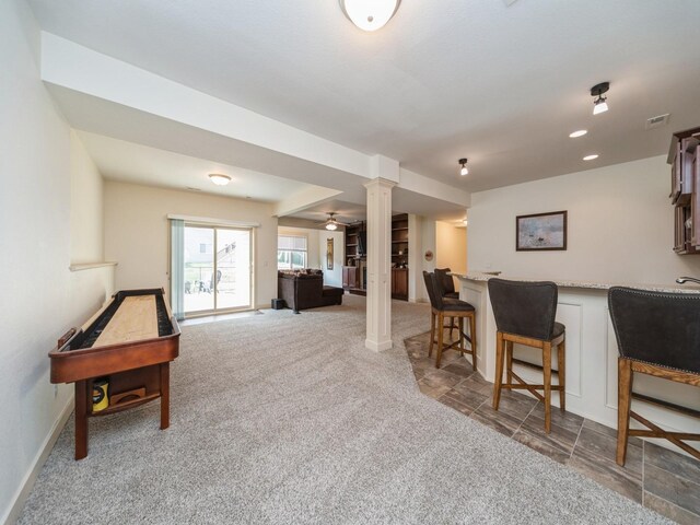 living area with carpet flooring, baseboards, visible vents, bar, and ornate columns