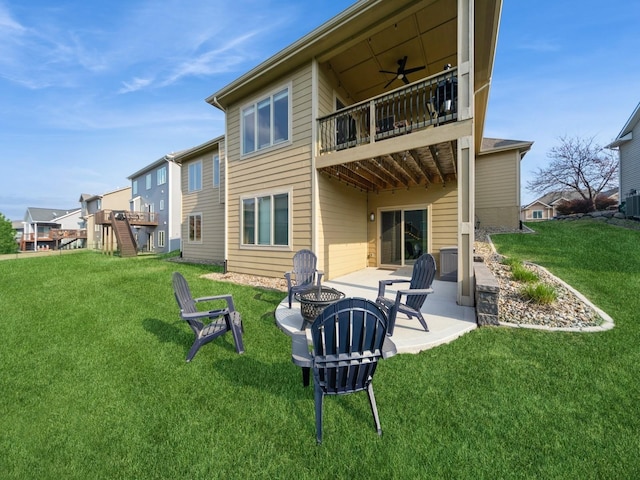 rear view of property featuring a fire pit, a lawn, a patio, and a balcony