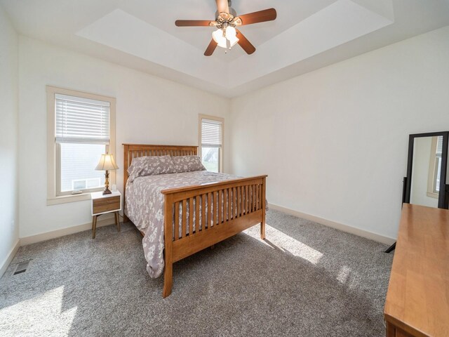 carpeted bedroom with baseboards, a ceiling fan, and a tray ceiling