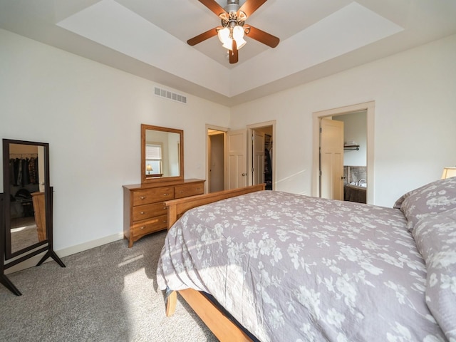 carpeted bedroom with a ceiling fan, a closet, a spacious closet, a raised ceiling, and visible vents