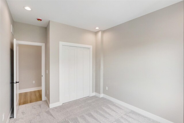 304 13th St NW, Bondurant, IA 50035 - unfurnished bedroom with light colored carpet, a closet, baseboards, and recessed lighting
