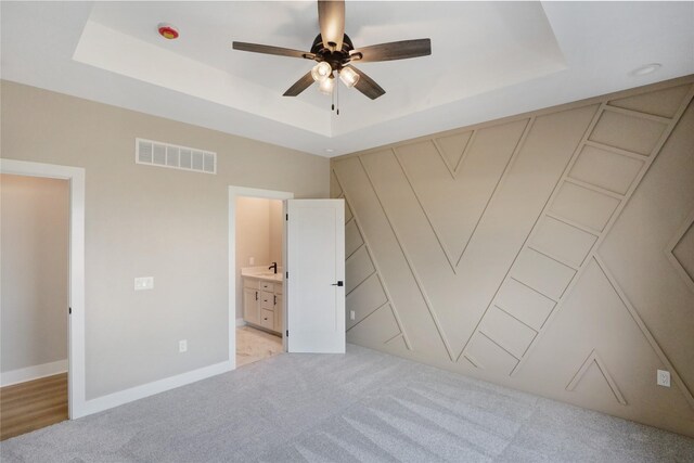 304 13th St NW, Bondurant, IA 50035 - unfurnished bedroom featuring a raised ceiling, light colored carpet, baseboards, a ceiling fan, and ensuite bathroom