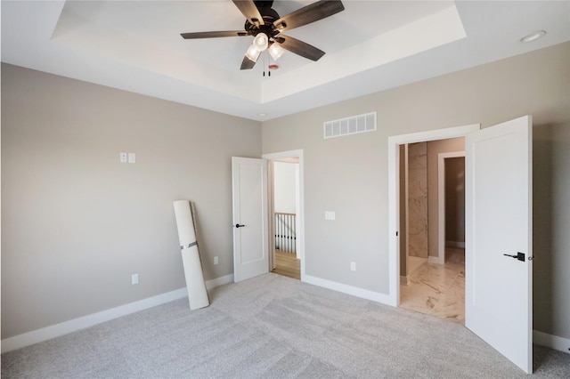 304 13th St NW, Bondurant, IA 50035 - unfurnished bedroom featuring a tray ceiling, light colored carpet, baseboards, and ceiling fan