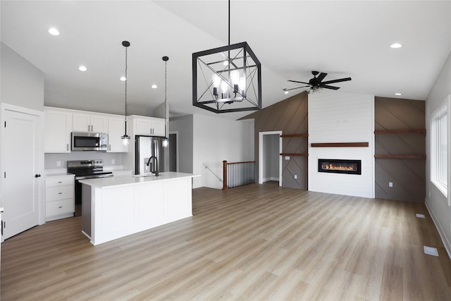 304 13th St NW, Bondurant, IA 50035 - kitchen with appliances with stainless steel finishes, high vaulted ceiling, light wood finished floors, an island with sink, and white cabinets