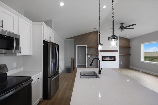 304 13th St NW, Bondurant, IA 50035 - kitchen with stainless steel appliances, a sink, a fireplace, white cabinetry, and a ceiling fan