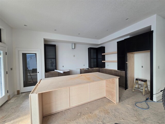 4611 Centennial Blvd, Urbandale, IA 50323 - kitchen with light carpet, dark cabinets, a textured ceiling, open shelves, and a kitchen island