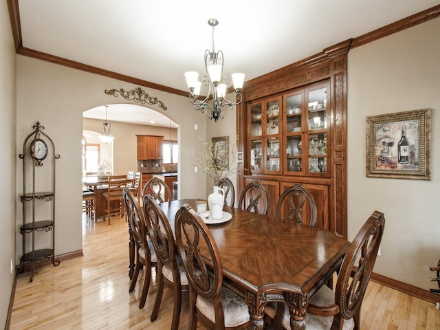 1835 SE Hillside Dr, Ankeny, IA 50021 - dining room featuring arched walkways, a chandelier, light wood-type flooring, and crown molding