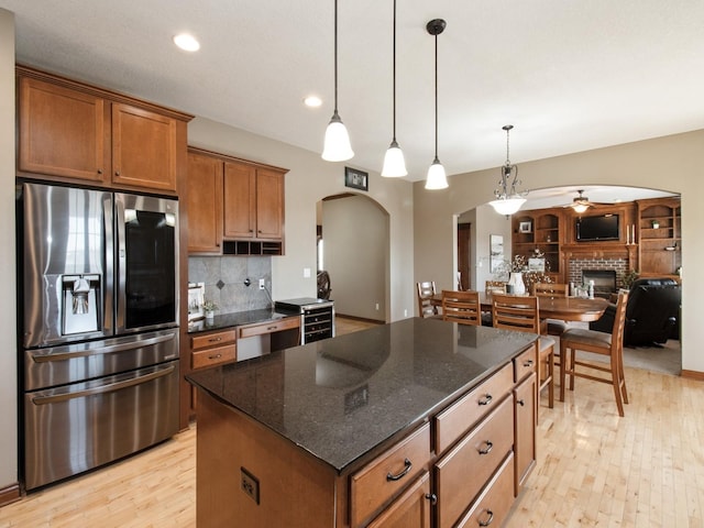 1835 SE Hillside Dr, Ankeny, IA 50021 - kitchen featuring stainless steel fridge, arched walkways, decorative backsplash, ceiling fan, and light wood finished floors