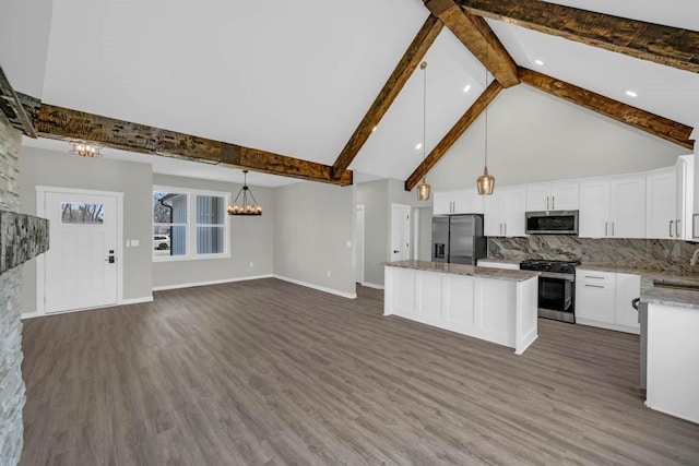 kitchen featuring stainless steel appliances, a center island, beam ceiling, an inviting chandelier, and backsplash