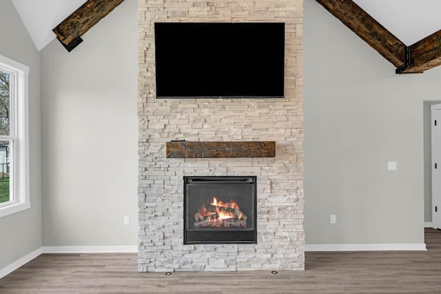 unfurnished living room featuring a stone fireplace, lofted ceiling, and wood finished floors