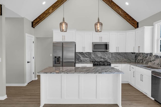 kitchen featuring backsplash, appliances with stainless steel finishes, a sink, and beam ceiling