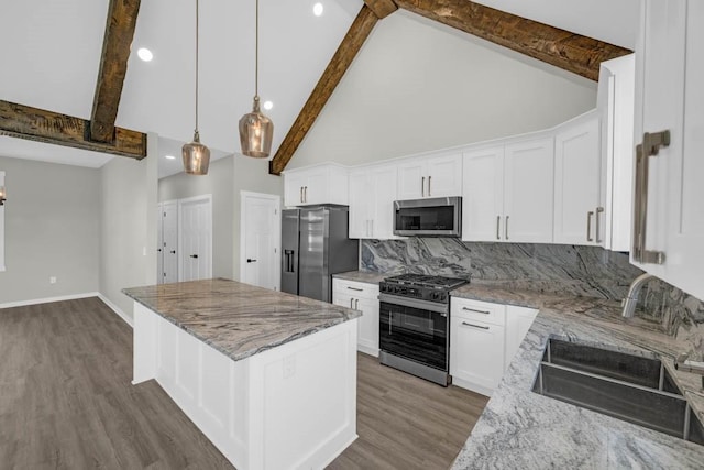 kitchen with a sink, beam ceiling, light stone countertops, a center island, and appliances with stainless steel finishes