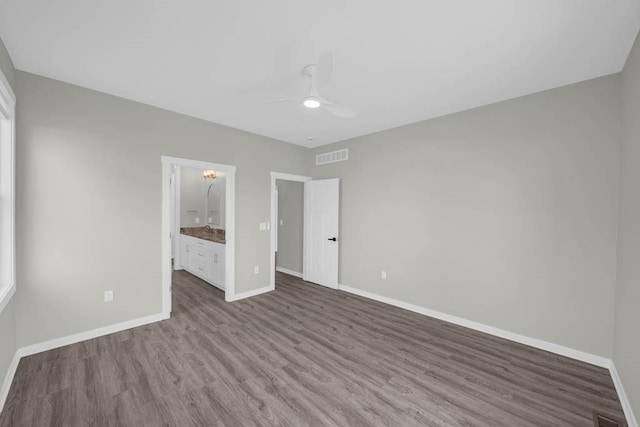 unfurnished bedroom featuring baseboards, wood finished floors, and visible vents