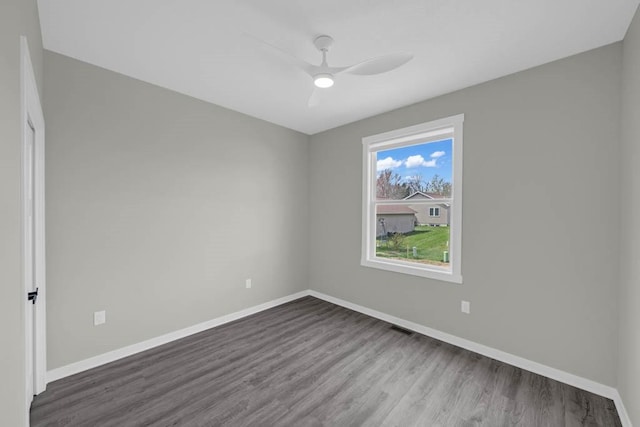 empty room with baseboards, a ceiling fan, and dark wood-style floors