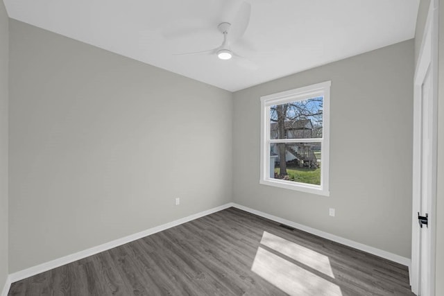 spare room featuring a ceiling fan, baseboards, and dark wood-style flooring