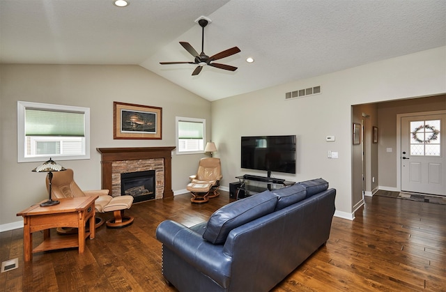 living room with a stone fireplace, visible vents, a ceiling fan, and wood finished floors