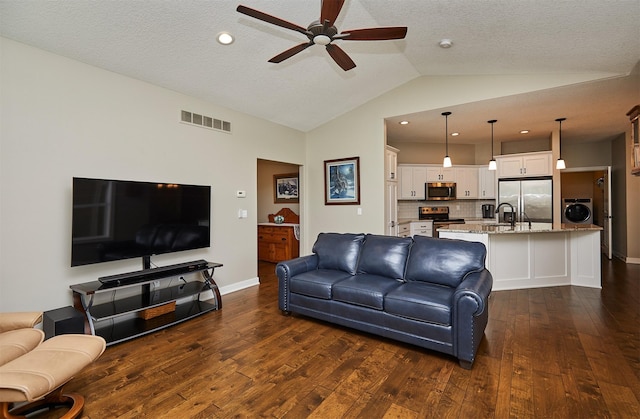 living room featuring lofted ceiling, dark wood-style floors, visible vents, ceiling fan, and washer / clothes dryer