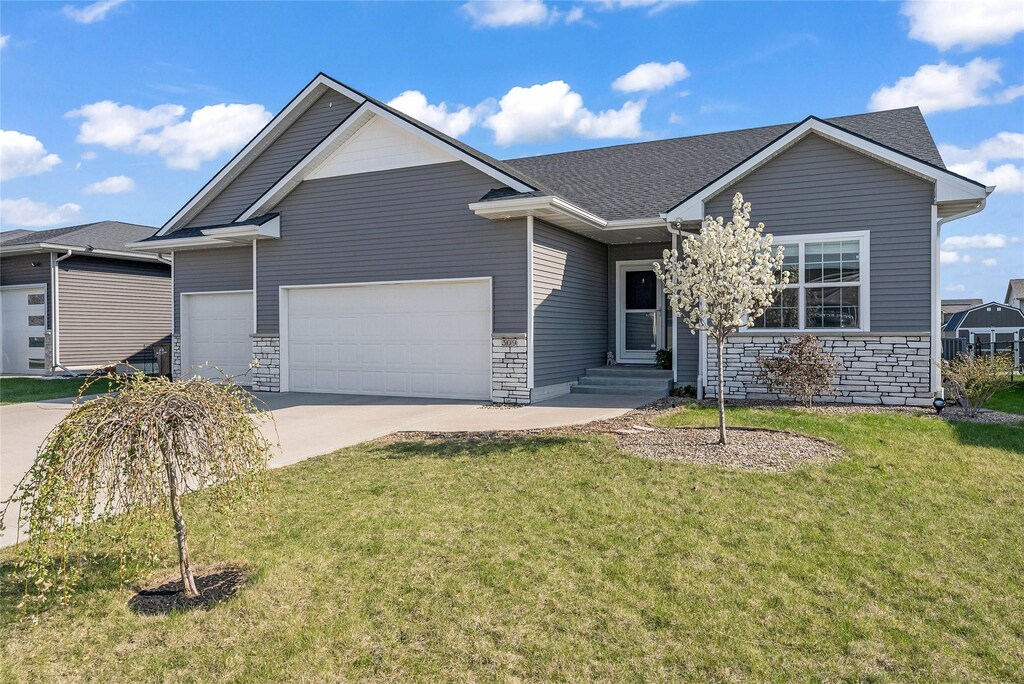 309 Summit Cir NW, Bondurant, IA 50035 - ranch-style house featuring stone siding, driveway, a front yard, and a garage