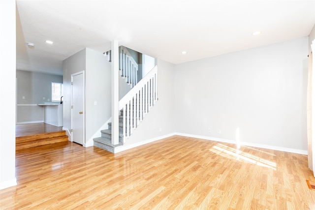 unfurnished living room with stairway, baseboards, wood finished floors, and recessed lighting