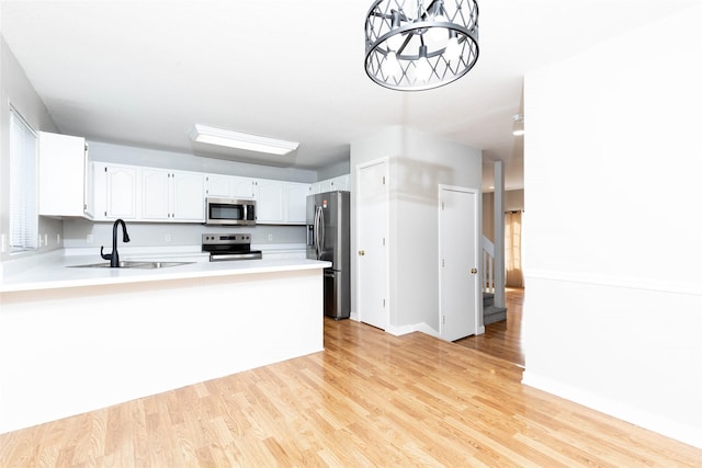 kitchen featuring light wood finished floors, light countertops, a sink, and appliances with stainless steel finishes