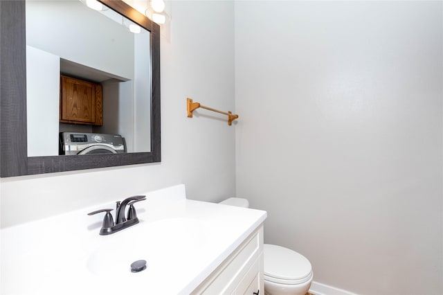 bathroom with toilet, vanity, and washer / dryer