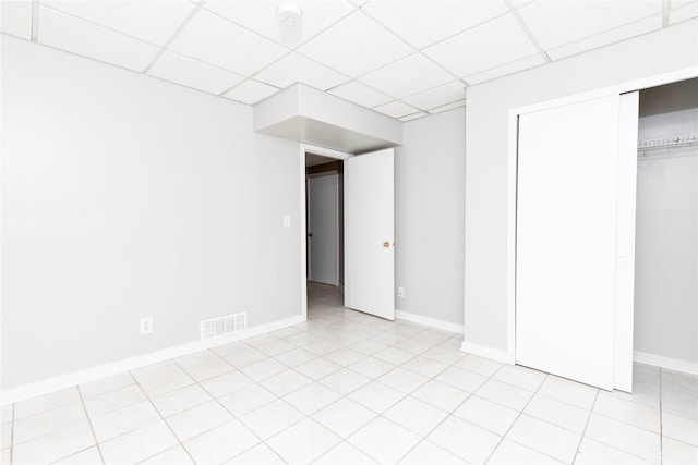 interior space with visible vents, a drop ceiling, baseboards, and light tile patterned floors