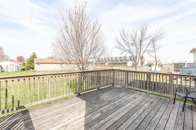 wooden terrace with a fenced backyard, a storage shed, a residential view, an outbuilding, and a lawn