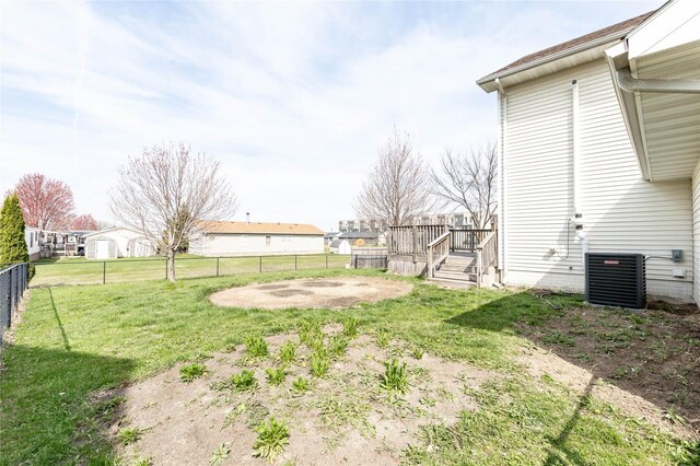 view of yard featuring central AC, a wooden deck, fence, and a residential view