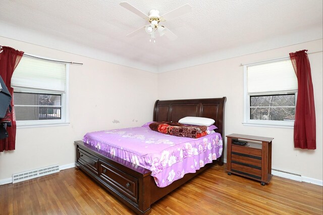 7422 Oak Brook Dr, Urbandale, IA 50322 - bedroom with a baseboard heating unit, baseboards, light wood finished floors, and visible vents
