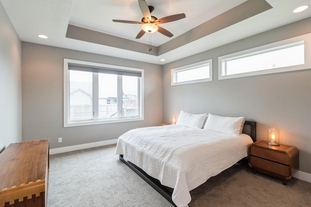carpeted bedroom featuring baseboards, recessed lighting, ceiling fan, and a tray ceiling