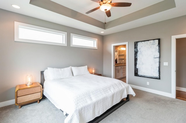 carpeted bedroom featuring recessed lighting, a raised ceiling, a ceiling fan, baseboards, and ensuite bathroom