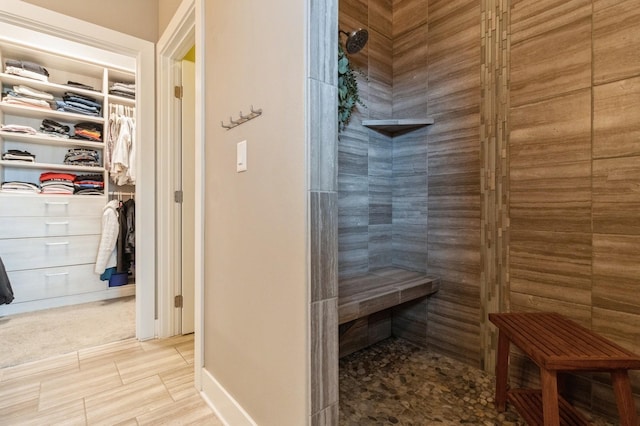 bathroom with a tile shower and a spacious closet