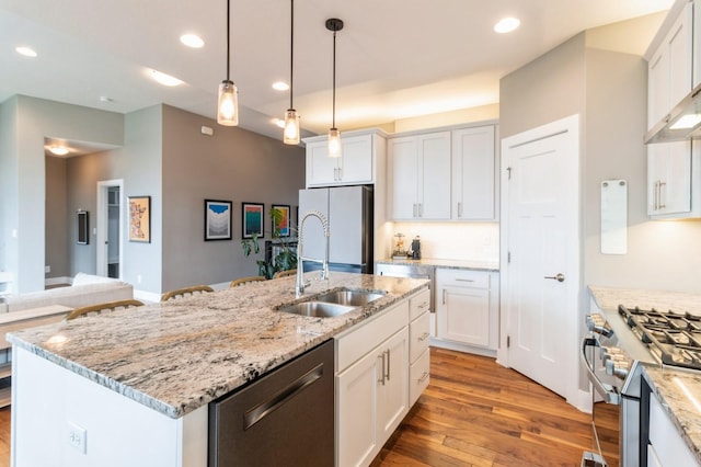 kitchen featuring a sink, light wood finished floors, decorative light fixtures, appliances with stainless steel finishes, and recessed lighting