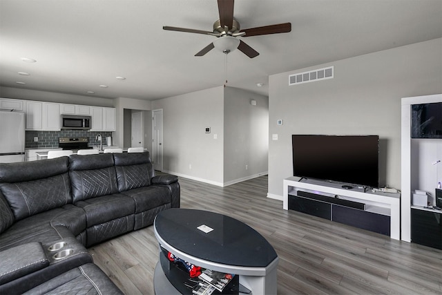living area featuring recessed lighting, wood finished floors, visible vents, a ceiling fan, and baseboards