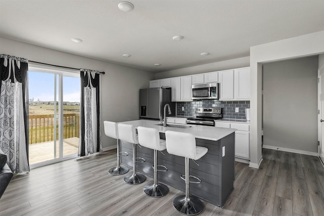kitchen with white cabinetry, an island with sink, stainless steel appliances, and a sink